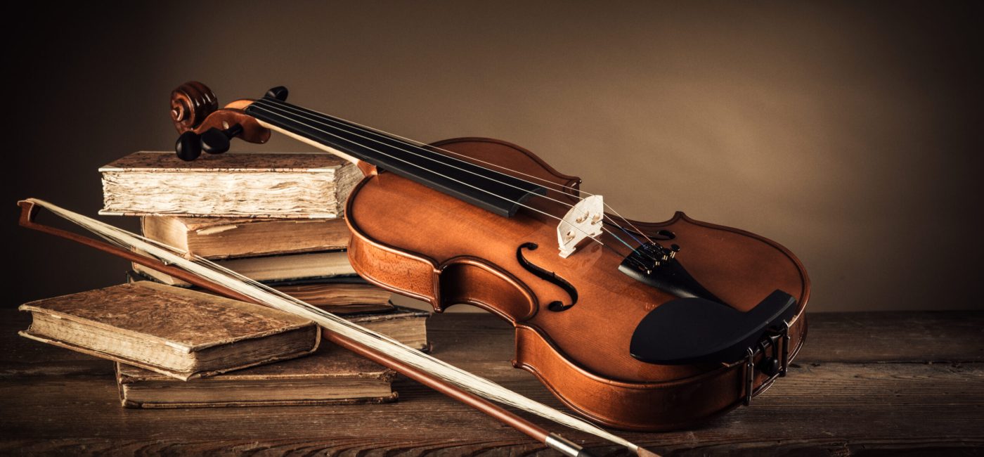 Violin, bow and old books on a rustic wooden table, arts and music concept